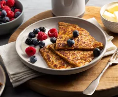 Sweet potato farls on a plate with cream and berries served with butter and a bowl of berries