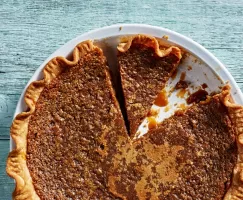 Tarte au Sucre, or sugar pie, in a white pie plate with two slices cut, one missing.