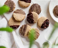 Vegan sugar cookies dipped and drizzled with chocolate on a cutting board