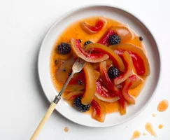 A plate of pickled watermelon rinds and blackberries with a long fork