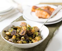 caramelized brussel sprouts in a white bowl with a spoon