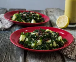 Two red bowls with Apple Kale Salad with Lemon Poppy Seed Vinaigrette